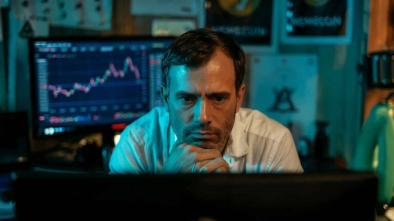 Investidor-serio-ao-assistir-live-com-grafico-de-criptomoedas-ao-fundo.jpg